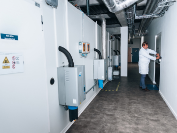 Laboratorijski tehničar približava se ATEX skladišnom prostoru u dugom, organiziranom hodniku unutar Eurofins skladišta. Scena naglašava kontrolirano okruženje i sigurnosne mjere postavljene za rukovanje i pohranu osjetljivih materijala.