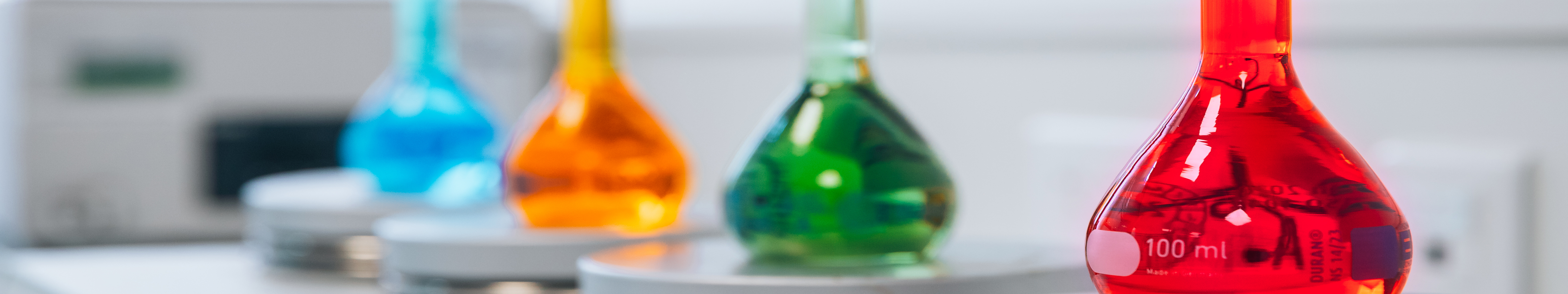 Četiri sterilizirane staklene bočice koje sadrže obojene otopine: plavu, žutu, zelenu i crvenu. Nalaze se u laboratoriji Eurofins BioPharma Product Testing.