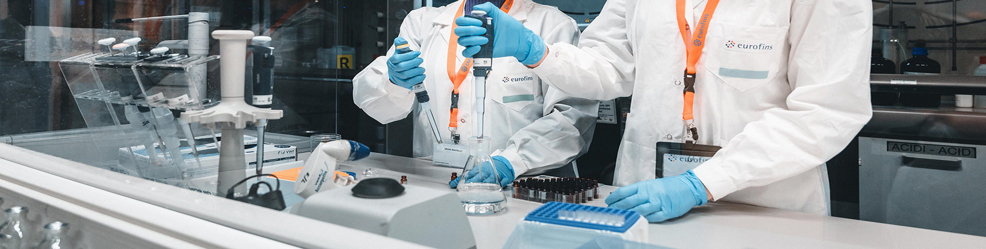 Dvije Istraživačice u laboratoriji, noseći laboratorijske mantile, rade s pipetama i medicinskim uređajima. Slika je povezana s uslugama medicinskih uređaja, s naglaskom na preciznost i stručnost u kliničkom ili istraživačkom kontekstu.