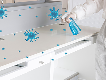 "Laboratorijski tehničar spreja plavu tekućinu na površinu, koja  sadrži biocide. Slika ističe primjenu kemijskih tvari za dezinfekciju i zaštitu od patogena u laboratorijskom okruženju.